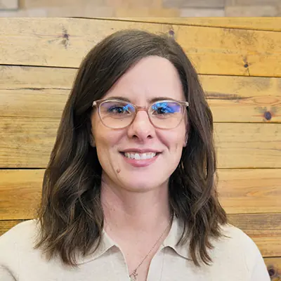 Jennifer, a Patient Care Coordinator, smiling at the camera in front of a wooden wall